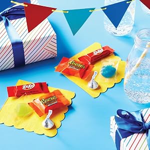 Hershey's Kisses candies, Kit Kat Miniatures bars and Reese's Miniatures cups on yellow napkins